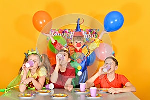 Three kids drink juice for a clownâ€™s birthday.