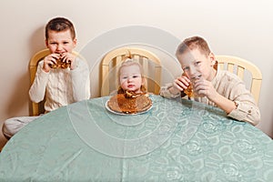 Three kids eating pancakes at the table at home