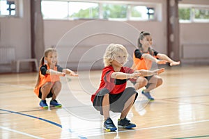 Three kids exercising in the gym and doing squats