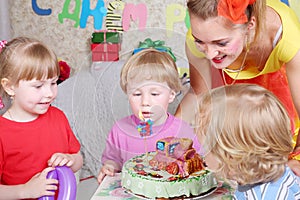 Three kids look at birthday cake with locomotive