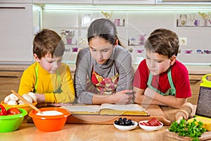 Three kids reading the cook book