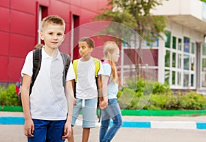 Three kids with rucksacks near school facade photo