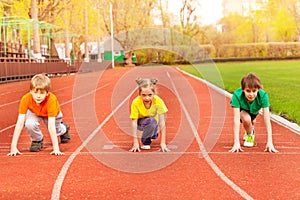 Three kids stand with bended knee ready to run