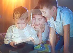 Three kids using tablet computer in a dark room