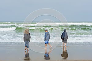 Three kids walking on ocean beach
