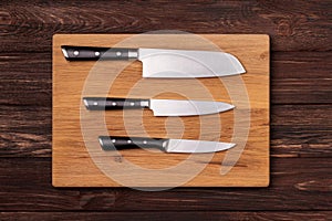 Three kitchen knives laying on a cutting board.