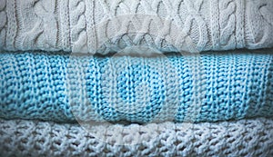 Three knitted wool warm sweaters are stacked in a neat pile. Clothing for cold winter days