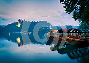 Three lake tour boats standing on famous bled lake with castle on the background and island church. Peaceful relaxing holiday photo