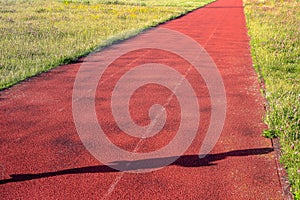 Three lanes of an athletics track with a shadow