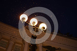 Three lanterns shine brightly in night Petersburg
