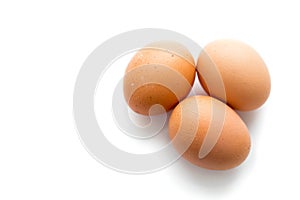 Three large brown chicken eggs on a white background with reflection.