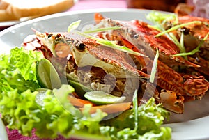 Three large red crabs with salad and lime