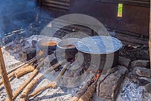 Three large saucepans resting on log fires