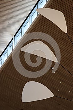 White mobile blades against light brown wood slat ceiling with pinprick can lights and square windows