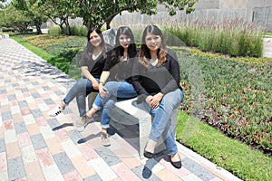 Three latin adult sisters as a loving family happily dressed in black outdoors in a park in harmony, freedom and happiness