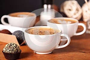 Three latte cups and small cakes on the wooden table in the cafe. Communication over a Cup of coffee, Coffee break