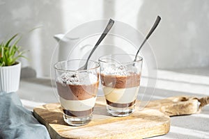 Three-layer chocolate and vanilla mousse dessert in glass cups, sprinkled with coconut flakes, on a children's