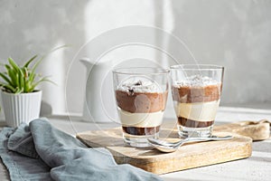 Three-layer mousse dessert made of chocolate and vanilla, decorated with fresh raspberries and coconut flakes in glasses