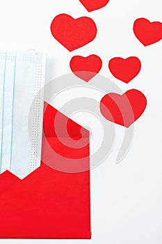 Three-layer protective mask in an envelope and hearts. Gift for Valentine`s Day in a pandemic due to covid-19. New norms.