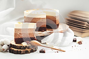 Three layered chocolate mousse cake on the wooden stand on white background. Good morning with fresh coffee and chocolate souffle