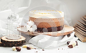 Three layered chocolate mousse cake on the wooden stand on white background. Good morning with fresh coffee and chocolate souffle