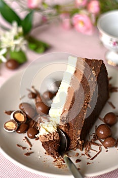 Three layers of chocolate cream cake, slice on a plate, spoon taking a piece.