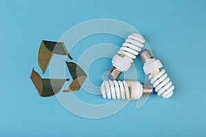 Three leaves of ficus and Three Energy saving lamp in shape eco green energy recycling isolated on the blue, caption for