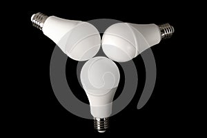 Three led bulb light and energy-saving lamp on table on black background