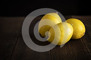 Three lemons on a rough wooden surface