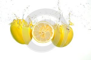 Three lemons spash in water on white