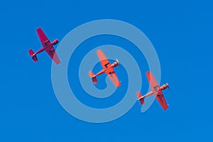 Three light-engine turboprop red aircraft fly in formation in a straight line in the sky