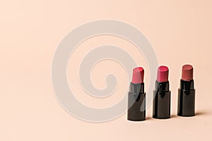 Three lipstick samples on a beige background.