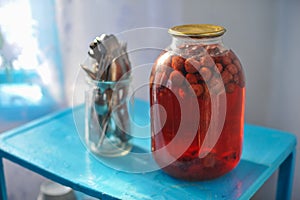 Three-liter glass jar with strawberry compote canned on blue tab