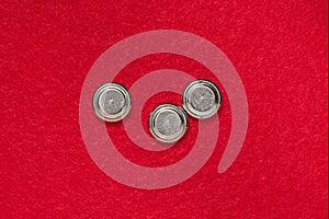 Three lithium button cell batteries, round batteries on a red background
