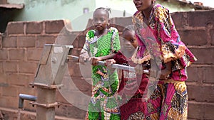 Three Little African Girls Troubeling Pumping Up Water At The Village Well