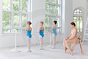 Three little ballerinas dancing with personal ballet teacher in dance studio