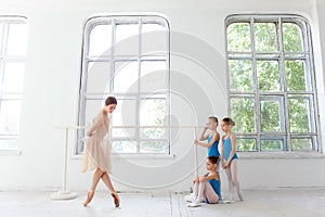 Three little ballerinas dancing with personal ballet teacher in dance studio