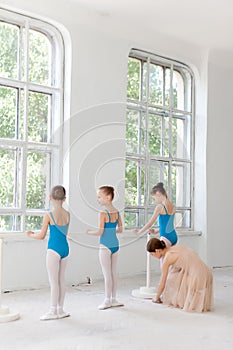 Three little ballerinas dancing with personal ballet teacher in dance studio