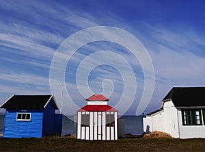 Three little brightly-painted wooden beach huts, Aero Island, Denmark