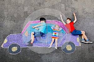 Three little children, two school kids boys and toddler girl having fun with with car picture drawing with colorful
