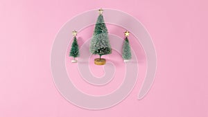 Three little Christmas trees with stars on the top appear on pastel pink theme. Stop motion