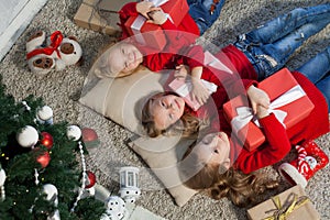 Three little girls blonde lying on the floor new year Christmas tree gifts