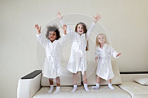 Three little girls dancing on the couch.
