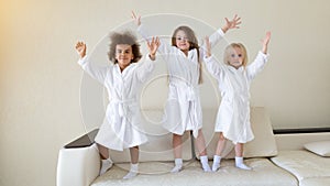 Three little girls dancing on the couch.