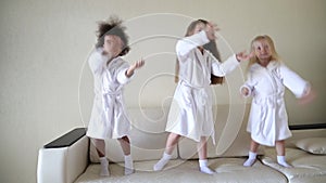 Three little girls are jumping on the couch.