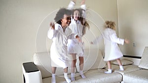 Three little girls are jumping on the couch.