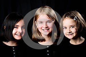 Three little girls posing on a black background
