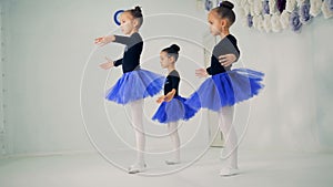 Three little girls are practicing ballet movements