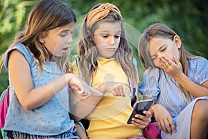 Three little girls using smart phone.