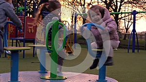 Three little Happy Children having fun spinning on merry-go-round. Smiling Siblings friends playing outside. emotional